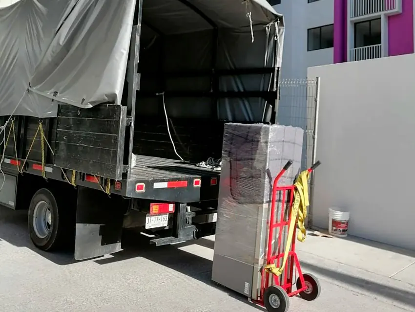 Diablito de carga junto a muebles envueltos listos para subir