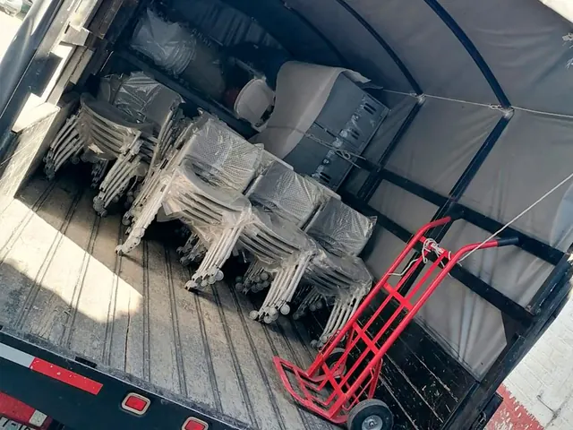 Sillas de oficina apiladas y diablito dentro de la caja